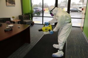 A person in a protective suit performing carpet cleaning and disinfection in an office at Mpls Janitorial Services in Minneapolis, MN.