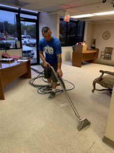 A professional from TLC Carpet Cleaning, Inc. cleaning carpet in an office space in Lewisville, TX.