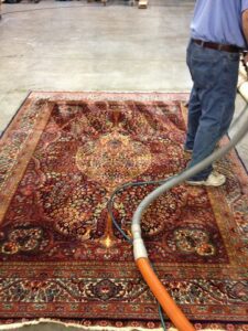 A carpet contractor cleaning a large ornate area rug with professional equipment at J L Williard Carpet Care in High Point, NC
