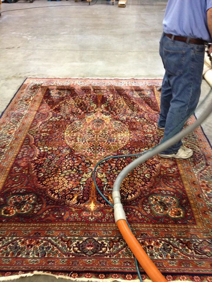 A professional cleaning an ornate area rug with a carpet cleaning machine at J L Williard Carpet Care in High Point, NC.