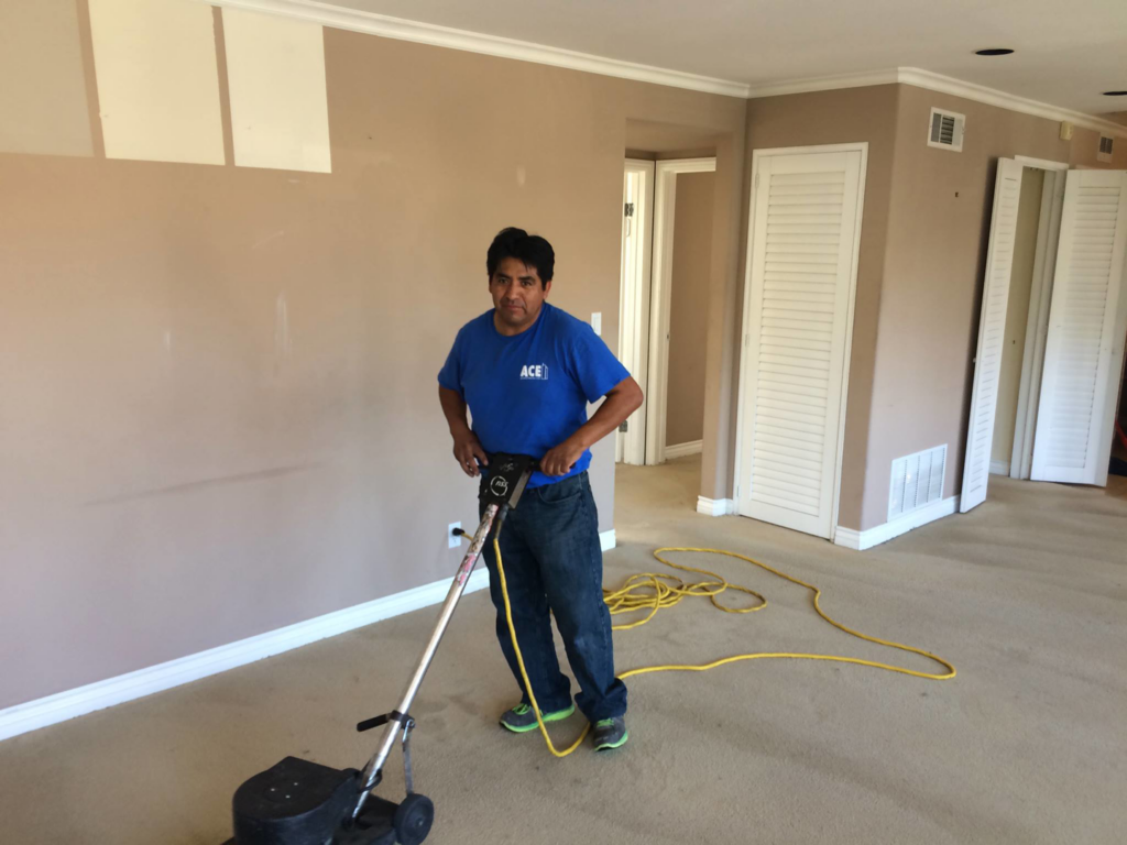 A professional from Ace Janitorial Services, Inc. operating a rotary carpet cleaning machine on a carpeted floor in San Diego, CA.