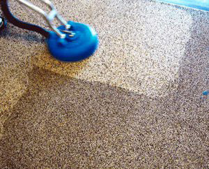 A rotary scrubber cleaning a carpet, showing a clear difference between cleaned and uncleaned areas by Carpet Care Express in Garland, TX