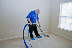 A professional performing carpet cleaning with an extractor wand in a room, provided by Klean Plus Commercial Cleaning in Sandy, UT.