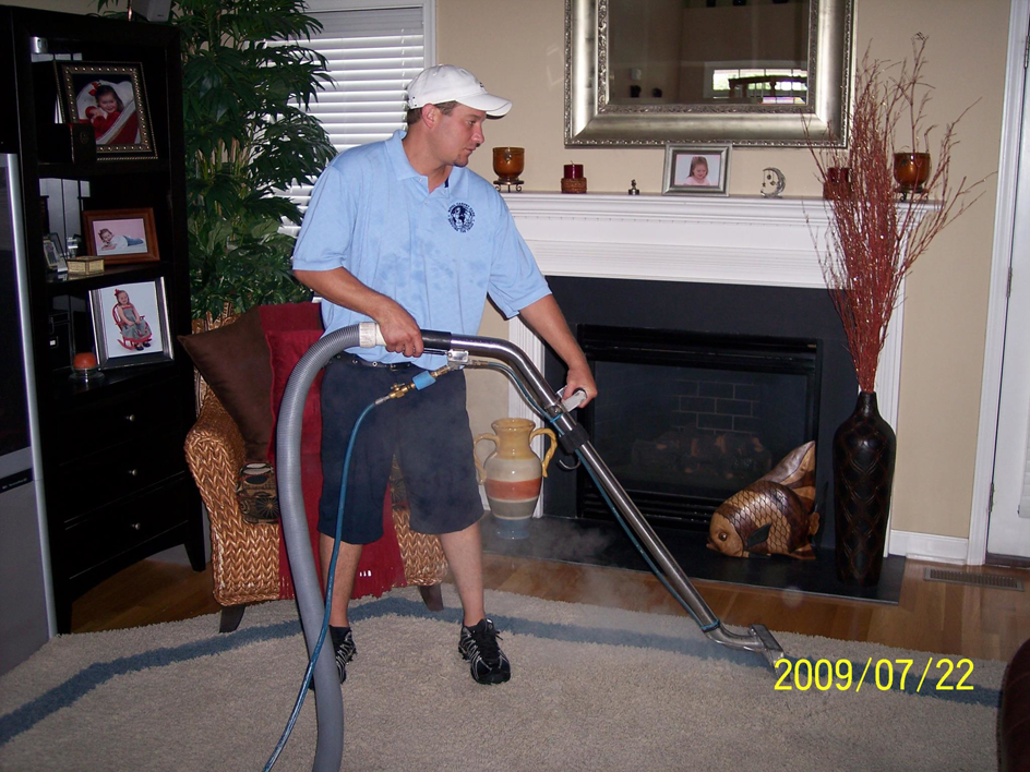 A professional performing carpet cleaning service on an area rug in a living room at Royal Carpet Care in West Babylon, NY.