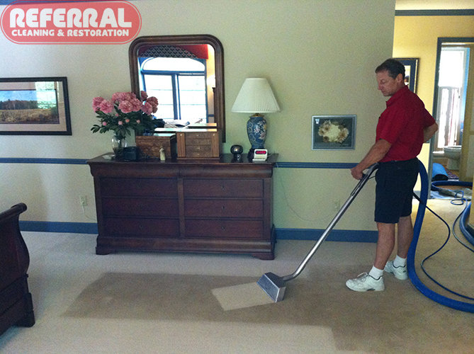 A technician performing carpet cleaning services with a wand, showing a clean path, at Referral Cleaning and Restoration Inc. in Fort Wayne, IN.