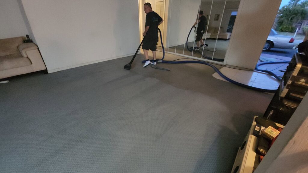 A technician performing residential carpet cleaning service with an extractor at Healthy Homes Cleaning and Restoration LLC in Fort Lauderdale, FL.