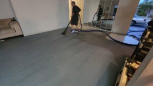 A technician performing residential carpet cleaning service with an extractor at Healthy Homes Cleaning and Restoration LLC in Fort Lauderdale, FL.