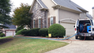 A carpet cleaning service van with hoses connected to a house by Extreme Carpet Cleaning Atlanta, GA.