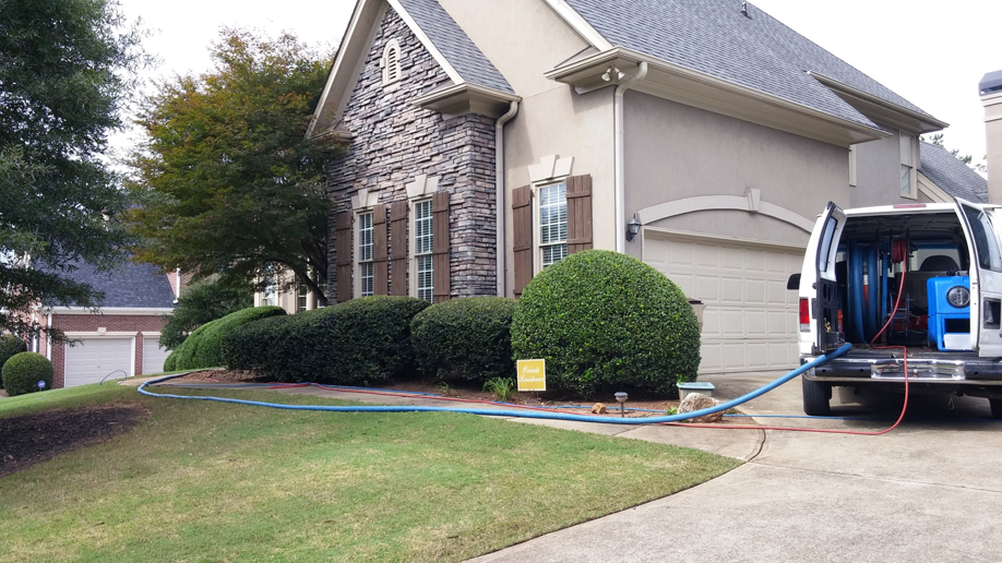 A carpet cleaning service van with hoses connected to a house by Extreme Carpet Cleaning Atlanta, GA.