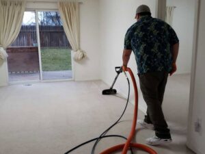A worker performing carpet cleaning service with a wand and hoses for Alaska Dry Carpet in Anchorage, AK.