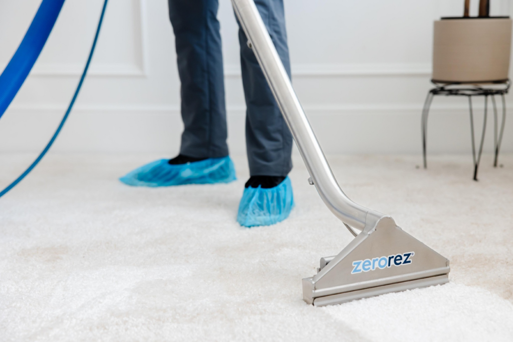 A Zerorez technician cleaning a white carpet with a professional wand in Charlotte, NC.