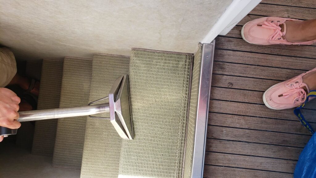 A professional from Anderson Certified, INC. cleaning carpeted stairs inside a boat in Chicago, IL.