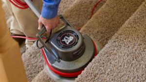 A professional cleaning carpeted stairs with a rotary machine at Heaven's Best Carpet Cleaning in Concord, NC.