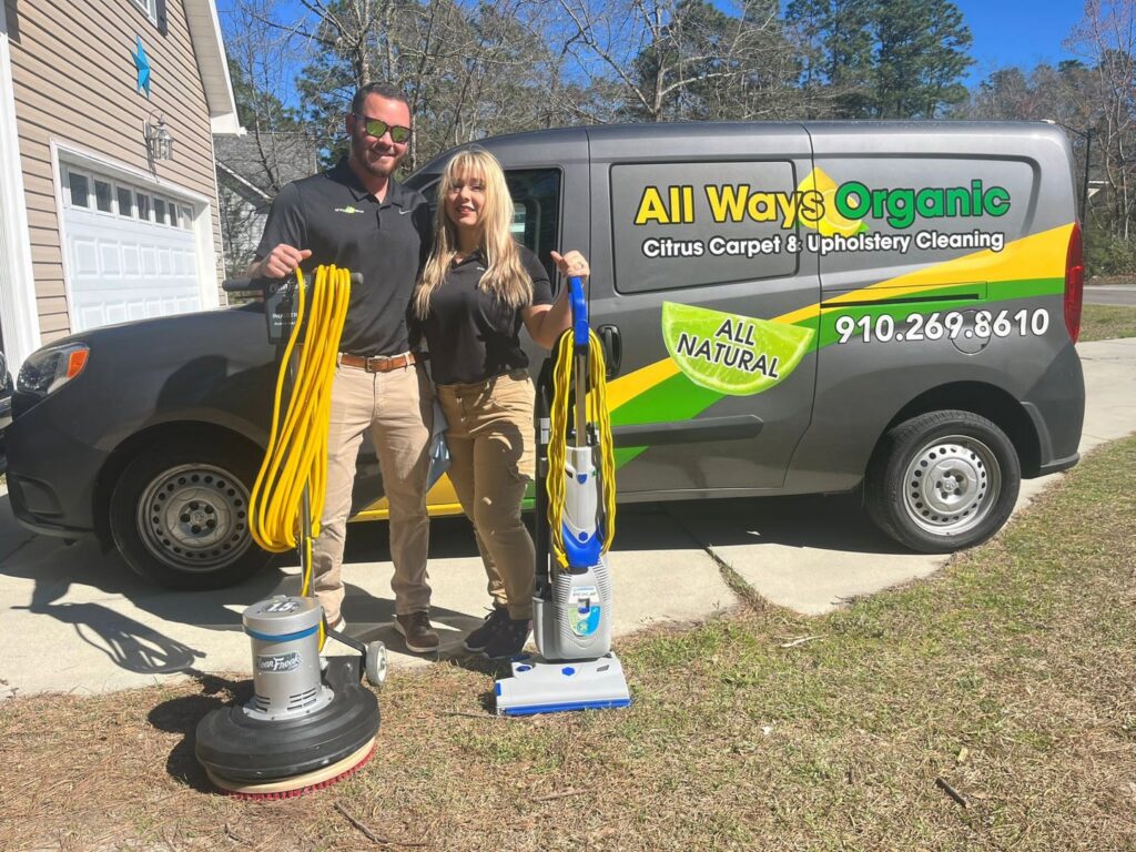 Two employees with professional carpet and upholstery cleaning equipment in front of their service van for All Ways Organic Citrus Carpet & Upholstery Cleaning in Wilmington, NC.