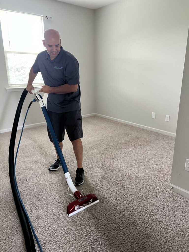 A BeClean technician in Charlotte, NC, actively cleaning a residential carpeted room with professional equipment.
