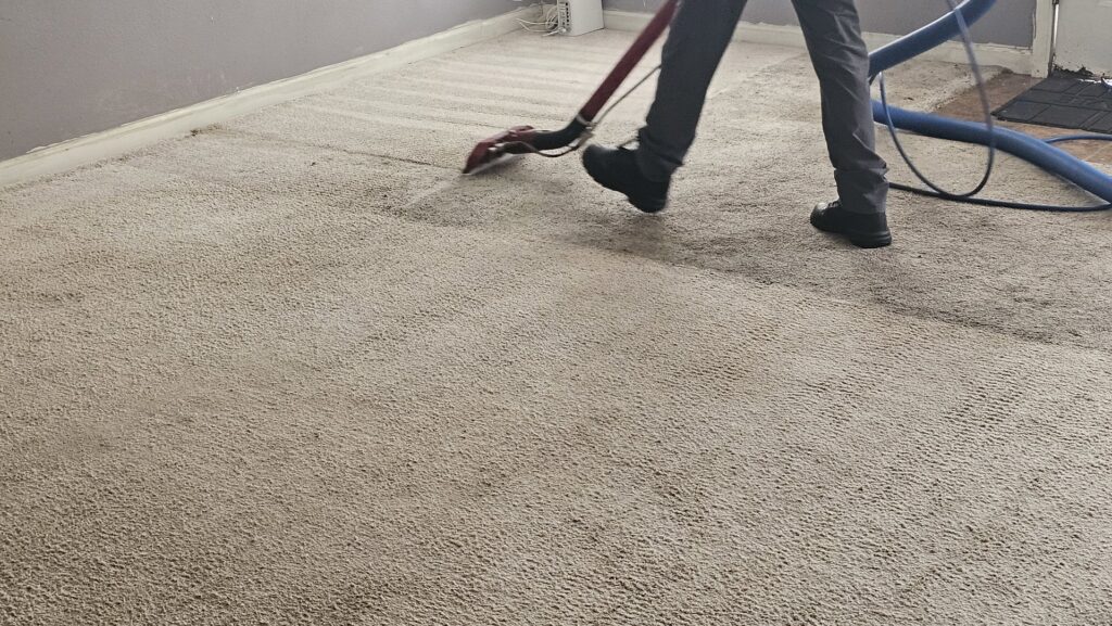 A carpet cleaning technician using a wand to deep clean a residential carpet for Carpet Chemistry in Gulfport, MS.