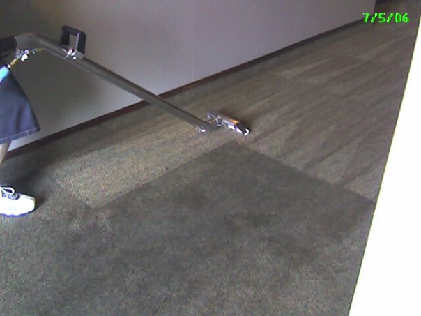 A carpet cleaning technician operating a wand, showing a clean section of carpet by JP Carpet & Tile Care in Sherman Oaks, CA.