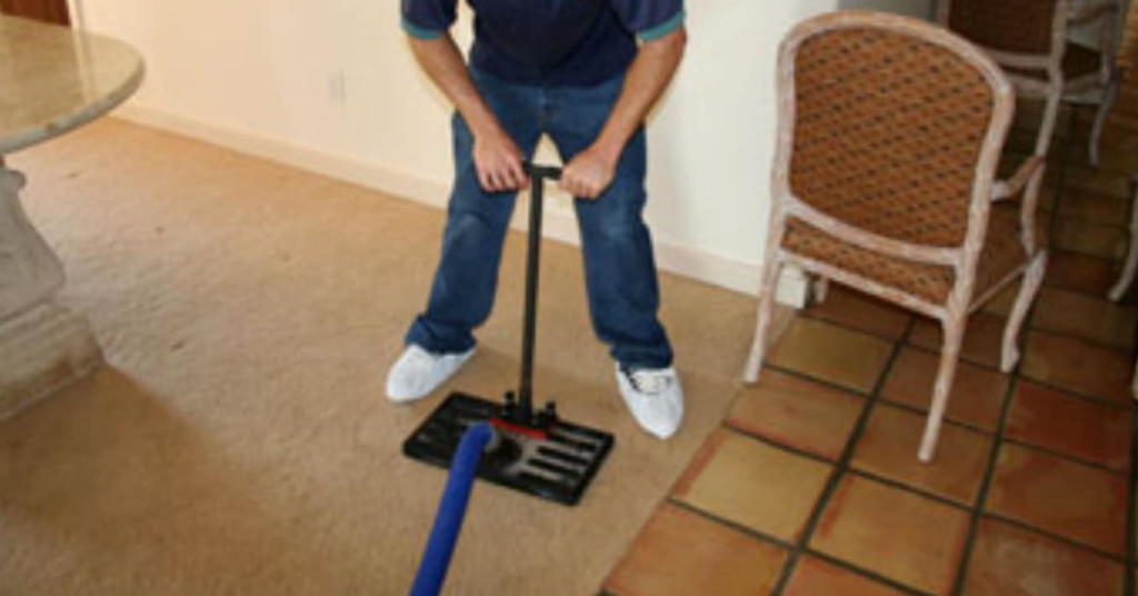 A carpet cleaning technician using a wand tool to clean a carpet for Promarc Carpet Care in Pine Bluff, AR.