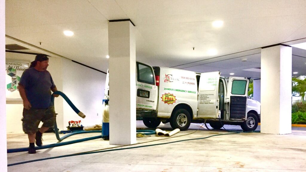 A technician from Celtic Carpet Cleaner setting up equipment and hoses from a branded van for a job in Fort Lauderdale, FL.
