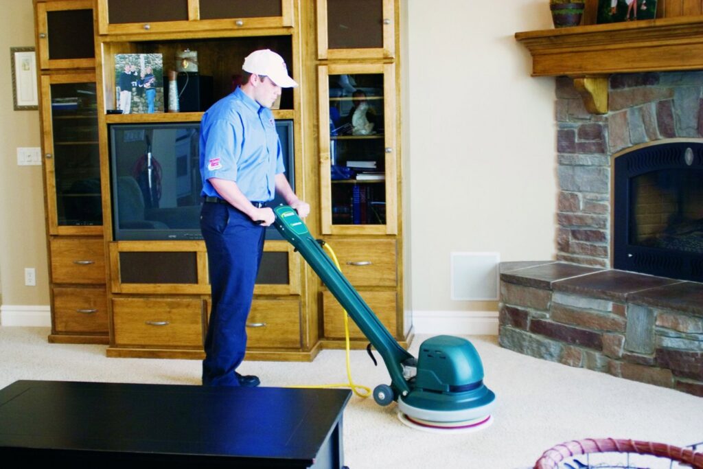 A professional carpet cleaning technician operating a machine in a living room at Heaven's Best Carpet Cleaning San Diego CA.