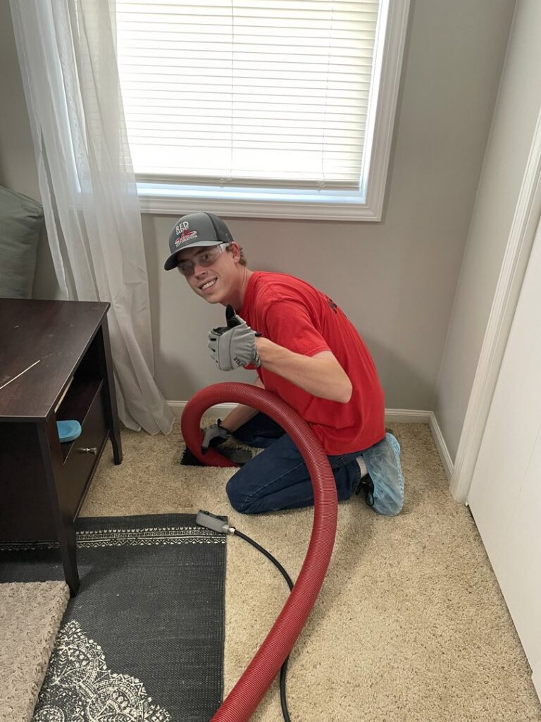 A Red Carpet Restoration technician professionally cleaning carpet in a home in Olathe, KS, ensuring a fresh and spotless finish.