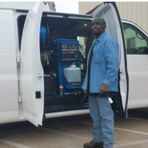 A carpet cleaning technician stands by a van with professional cleaning equipment from Crawford's Carpet Cleaning in Oklahoma City, OK.