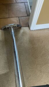 A carpet cleaning tool positioned at the edge of a carpeted room next to tile, ready for a job by Safe Solutions Carpet Cleaning in Franklin, TN.