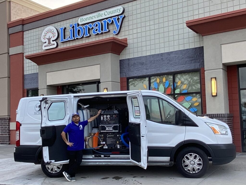 A B of C Carpet Cleaning LLC technician standing proudly next to their branded service van with cleaning equipment in Idaho Falls, ID.