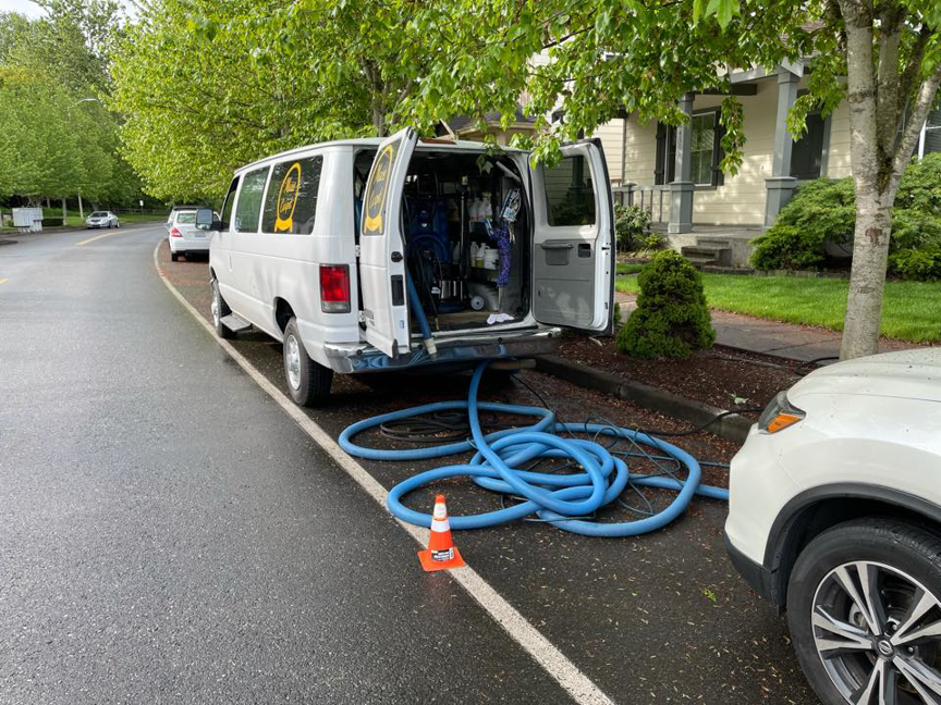 A professional carpet cleaning van with equipment and hoses set up for a job by Mace Carpet Services in Tacoma, WA
