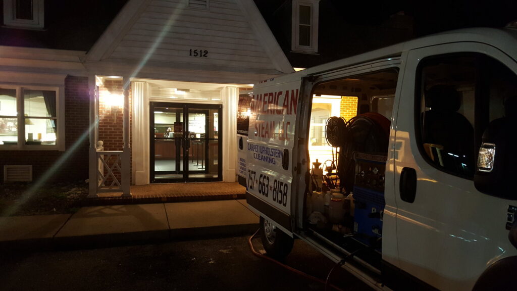 American Steam's carpet cleaning van with equipment visible, parked outside a client's building at night in Suffolk, VA.