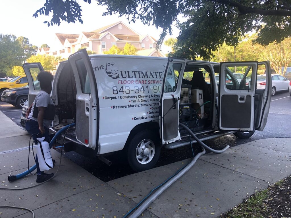 A service van with carpet cleaning equipment and a technician working at The Ultimate Floor Care Services in Hilton Head Island, SC