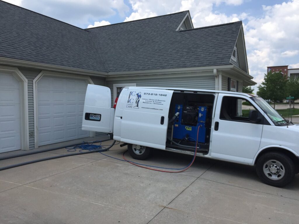 A C&C Carpet Care LLC van with cleaning hoses connected to a residential home in Columbia, MO.