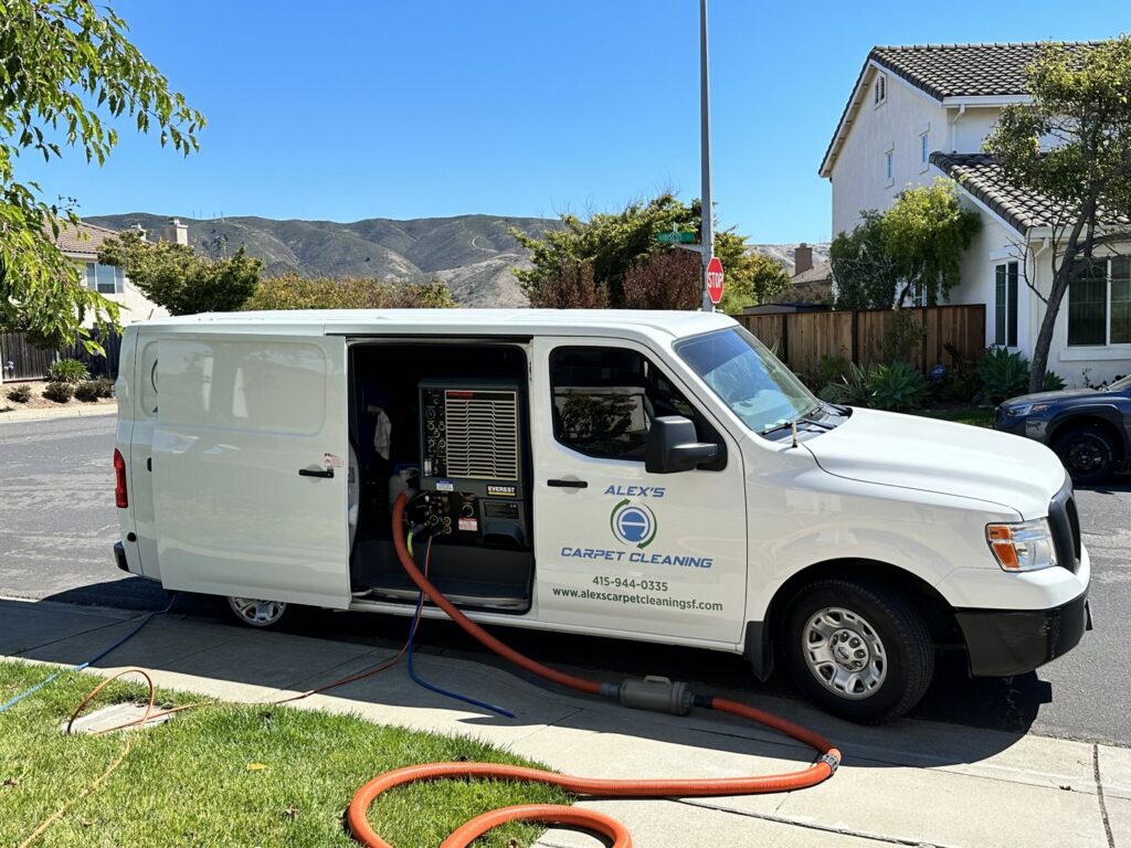 Alex's Carpet Cleaning van parked outside a house with hoses extended for a carpet cleaning job in Omaha, NE.