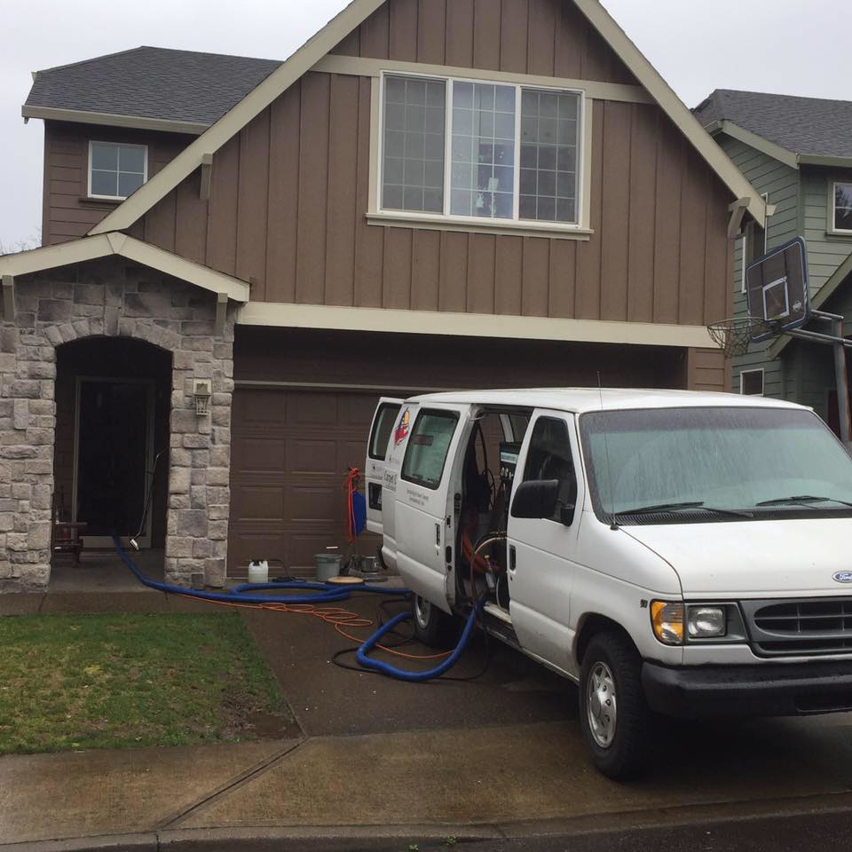 A Diamond Carpet Cleaning van with hoses running into a house, indicating a carpet cleaning job in progress in Portland, OR.