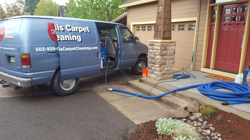 Howells Carpet Cleaning van parked outside a home with hoses connected, ready for a carpet cleaning job in Milwaukie, OR.