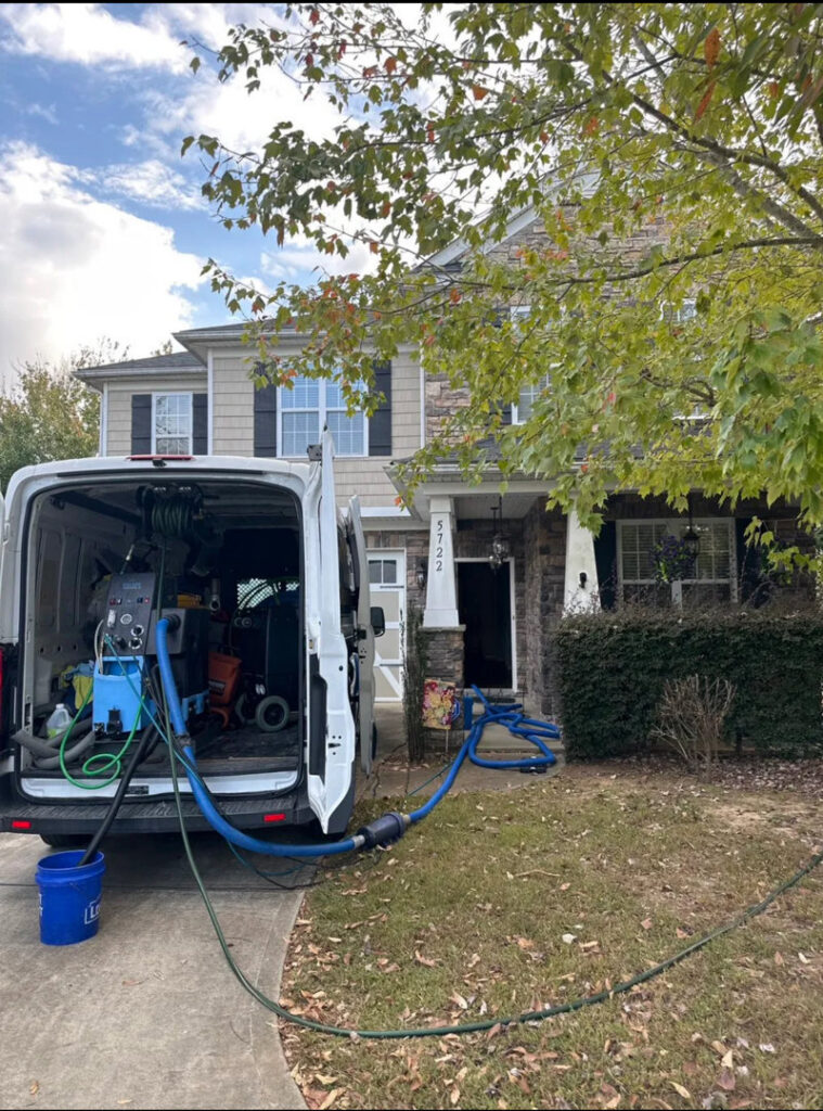 A professional carpet cleaning van parked outside a home with hoses extended, ready for service by Ype Cleaning LLC in Monroe, NC.