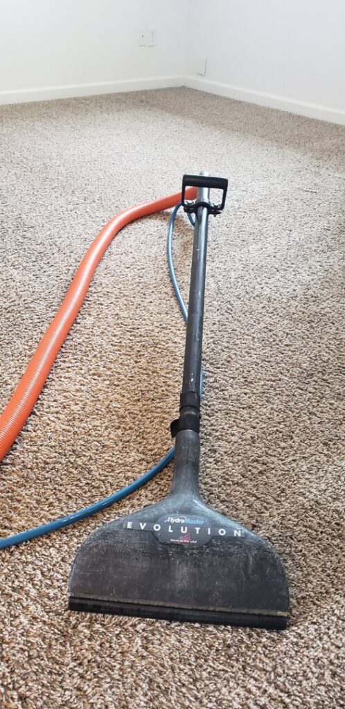 A carpet cleaning wand and hoses resting on a carpeted floor during a service by Alaska Dry Carpet in Anchorage, AK.