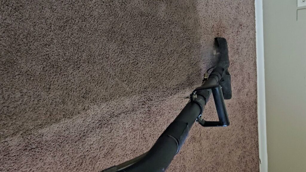 A carpet cleaning wand in action, showing a clean path on brown carpet by Andy's Cleaning Company LLC in Topeka, KS.