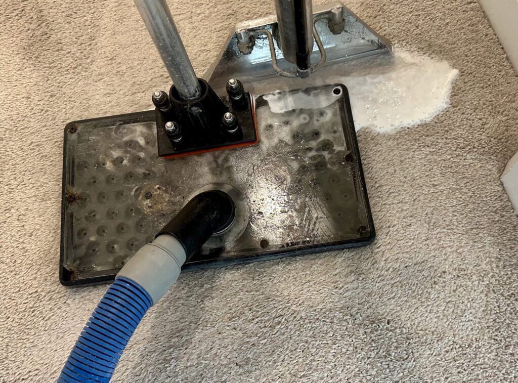 A carpet cleaning wand actively cleaning a carpet, showing suds and water extraction by Hi-Tech Carpet Cleaning in Elk Grove, CA.