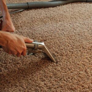 A close-up of a carpet cleaning wand being operated on a brown carpet by Premier Carpet Cleaning in Colorado Springs, CO.