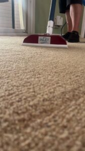 A carpet cleaning wand with the Inlet Services logo actively cleaning a carpet by Inlet Carpet Care in Virginia Beach, VA
