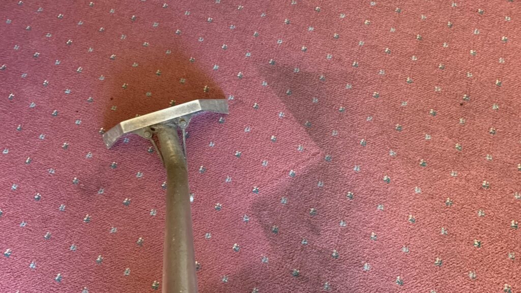 A carpet cleaning wand in action on a red patterned carpet, showing a clean path by Eagle 1 Carpet Cleaning in Reno, NV.