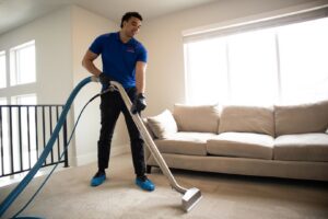 A professional using a carpet cleaning wand tool to clean a residential carpet for AJS Carpet Cleaning, Inc. in Orem, UT.
