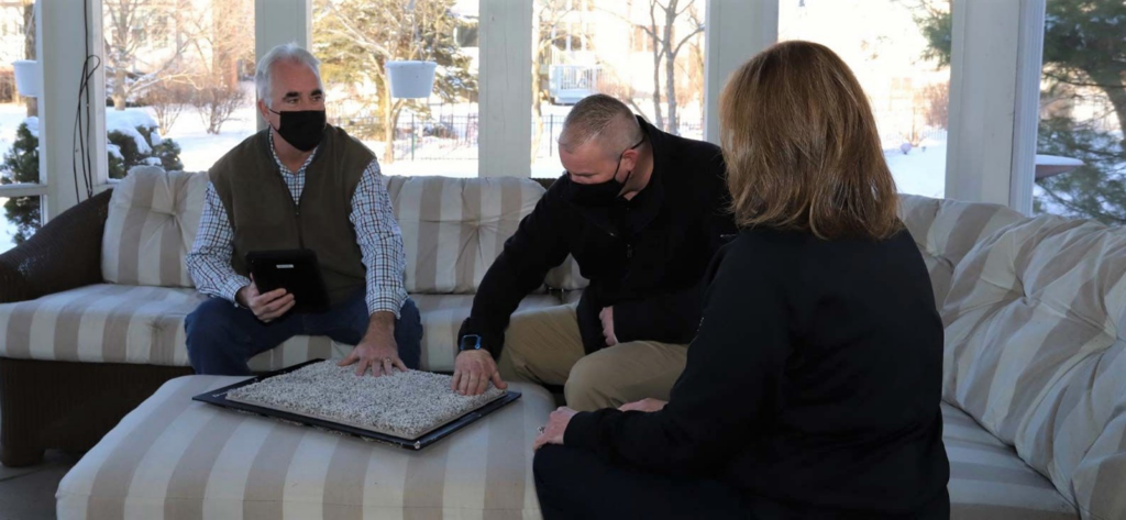 A carpet contractor from Carpets Direct Naperville, IL, showing carpet samples to clients during an in-home consultation.
