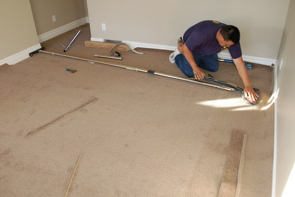 A carpet contractor using a power stretcher to professionally stretch and install carpet in a room for Huntsville Carpet Tech in Huntsville, AL.