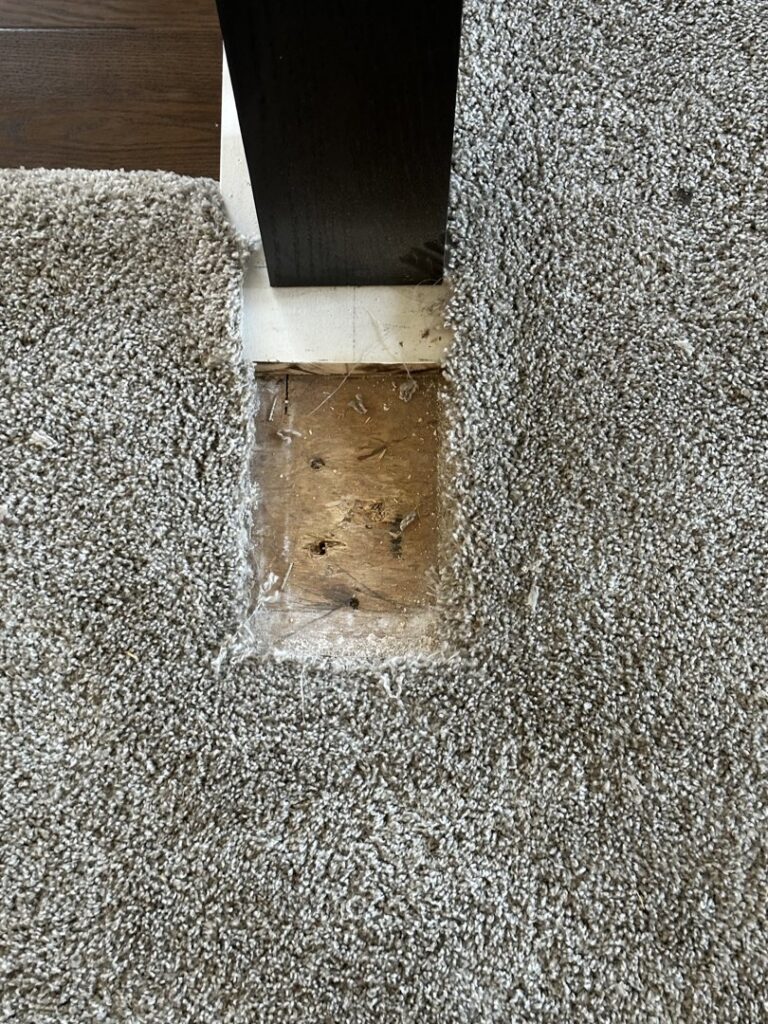 Carpet cut around a wooden post, exposing subfloor, demonstrating installation or repair by Mr. Carpet Cleaning Orlando, FL.