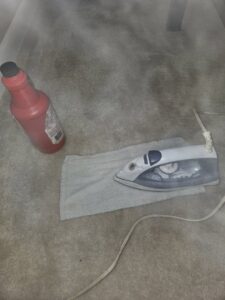 An iron and cleaning solution on a carpet, demonstrating a carpet dent removal or spot treatment technique by Hendry's Carpet Care in Tallahassee, FL.