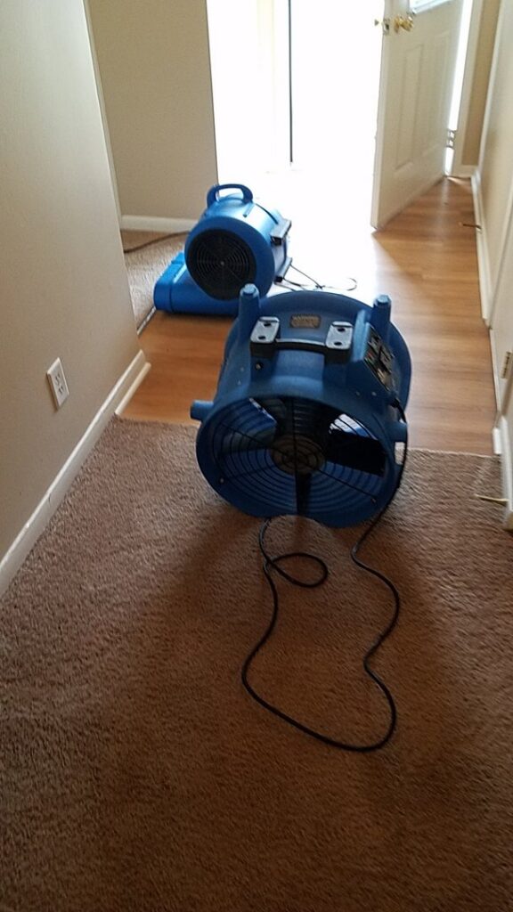 Two large blue air movers drying carpet and hardwood floors after water damage restoration by Inspection Ready LLC in Bellevue, NE.