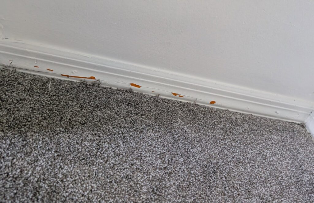 Detailed view of a grey carpet installation edge against a white baseboard by Carpet Cabin in Fort Smith, AR.