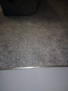 Close-up of a carpet edge with a metal transition strip, installed by Carpet Warehouse Lorain LLC in Lorain, OH.